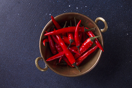 红色的小辣椒在库珀碗的黑暗背景。