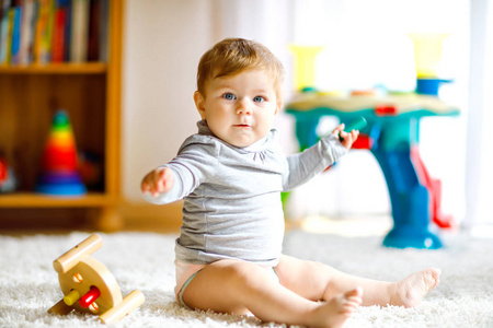 可爱的女婴玩教育玩具。快乐健康的孩子有乐趣与五颜六色的不同木制玩具在家里。自然玩具儿童的早期发育