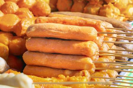 烤架上烤的木串上的香肠躺在桌子上，上面有一种传统的亚洲街头食品。 近点