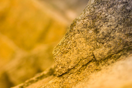 花岗岩岩石在橙色调色。 花岗岩靠近。 带有黄色的石头的纹理。 背景来自天然材料，颜色温暖
