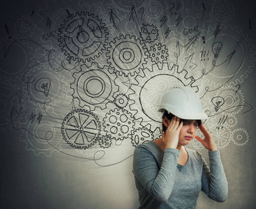 思考困难的女工程师头痛戴着带有齿轮脑箭头的防护头盔,思绪混乱.