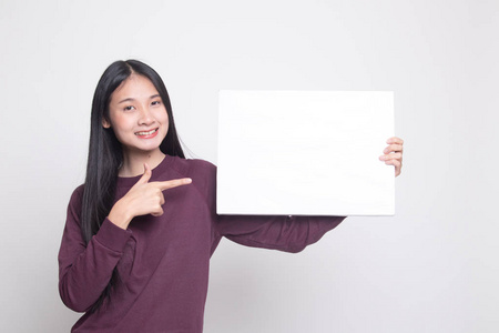 年轻的亚洲女人指着白色背景上的空白标志