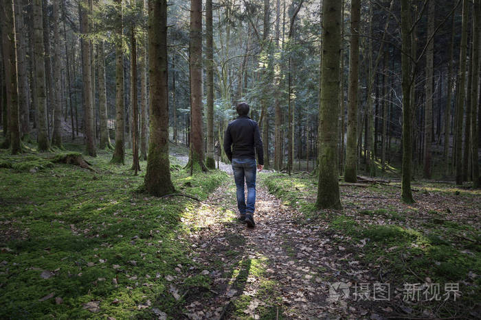 一个人独自走在苔藓般的森林小径上.