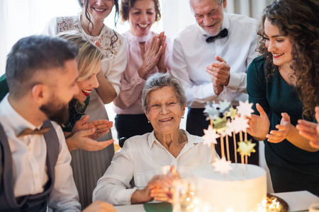 一位有多代家庭的老年妇女在室内聚会上庆祝生日
