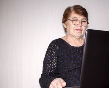 一位老妇人仔细阅读笔记本电脑上的信息，一位女士上网
