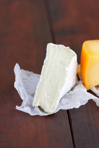 木板上的奶酪。 天然模糊背景下的各种奶酪。 羊皮纸上的DorbluCamembert和硬黄色奶酪。 复制空间