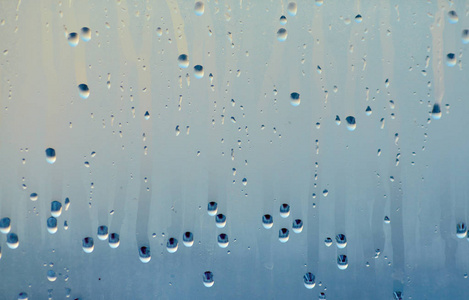 水滴在玻璃上。 窗户冷凝产生的天然水池背景