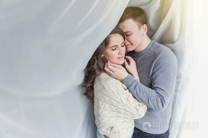 年轻女人拥抱男朋友的白色背景.