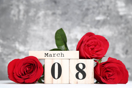 s Day on wooden calendar with red roses on grey background