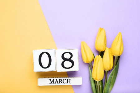 s Day on wooden calendar with yellow tulips on colorful backgrou