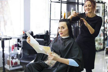专业的理发师准备给她美丽开朗的女客户理发。 美容业服务