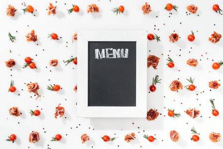 顶部的粉笔板，菜单字母在西红柿，意大利火腿，香料和叶子。