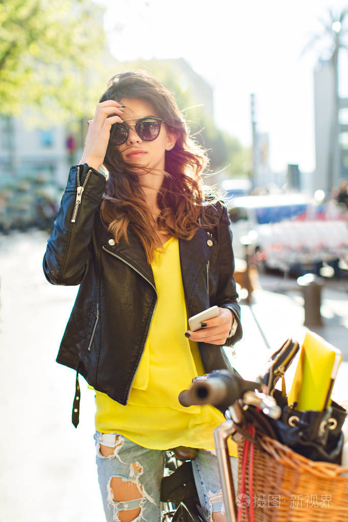 她穿着紧身衬衫, 黑色夹克, 在风中拉直头发