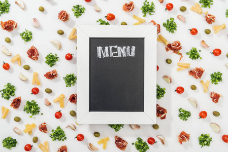 顶部的粉笔板，菜单字母在橄榄，意大利火腿，绿色植物，切奶酪，大蒜，丁香和樱桃番茄