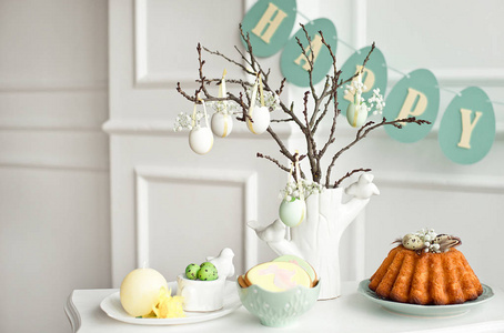 复活节餐桌的节日装饰一个带有树枝的花瓶，用花和鸡蛋饼干和兔子复活节蛋糕和糖果装饰