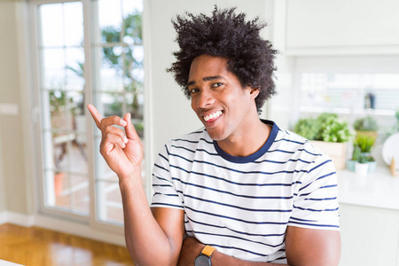 非裔美国人穿着条纹T恤，脸上挂着一个大大的微笑，用手和手指，看着相机。