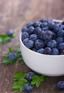 在木制桌面上的碗里近距离观看新鲜美味的蓝莓