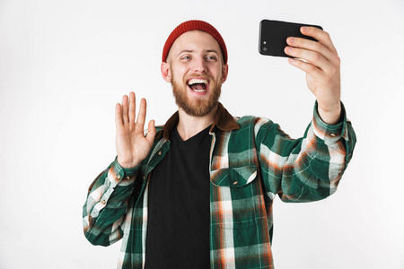 白种人戴着帽子和格子衬衫的形象，在手机上自拍照片，而站在白色背景上被隔离