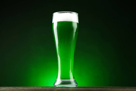 s Day. Glass of green beer on dark background