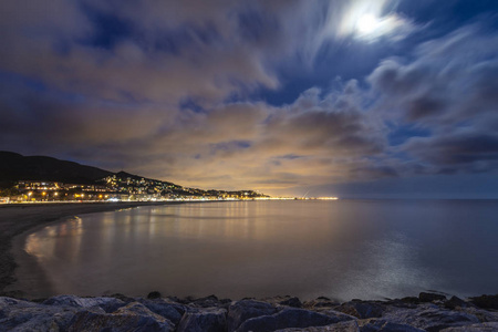 夜晚平静的海滩，壮观的天空和月亮照亮了城市背景加泰罗尼亚西班牙