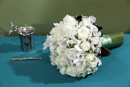 新娘花束。 花束与白色玫瑰和阿尔斯特罗米里亚斯为婚礼在绿色的桌子和配件。 婚礼的细节。