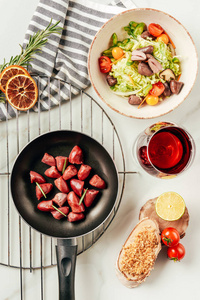 煎锅中的肉和带葡萄酒的沙拉的顶部视图