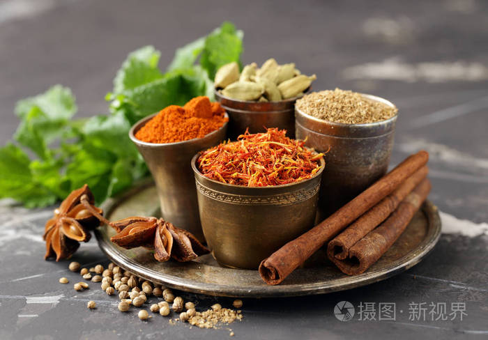 一套香料,藏红花,豆蔻和辣椒,装在金属碗里