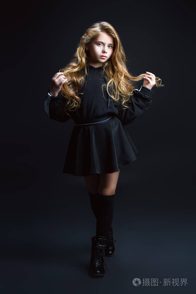 一个可爱的情感女孩在工作室的黑色背景上摆姿势的完整长度肖像.