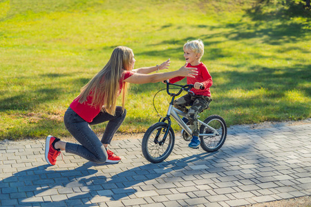 年轻的母亲教她的儿子如何在公园里骑自行车