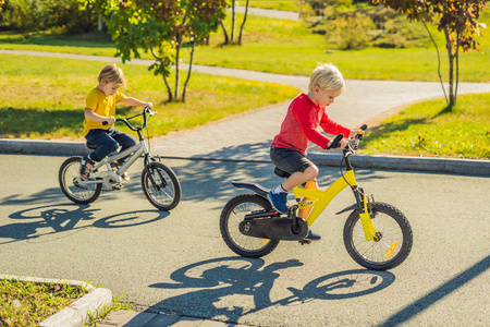 两个快乐的男孩在公园里骑自行车。