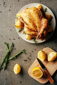 用柠檬和刀在盘子和砧板上的炸鸡的顶部视图