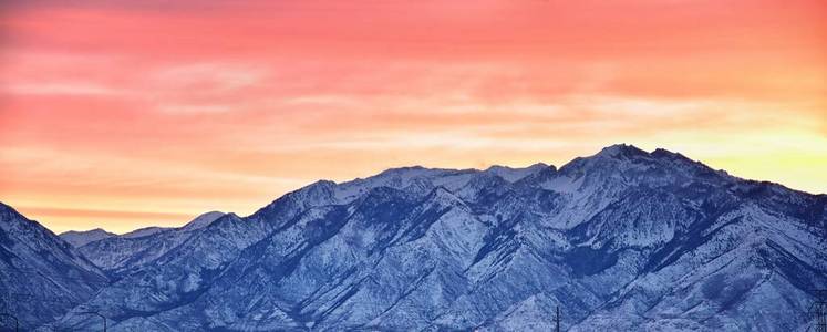 冬天的日出，雪顶的全景，在岩石山前，大盐湖谷和云景，从山景走廊公路。 犹他州美国。