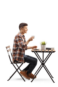 一个年轻人坐在咖啡馆里，喝着一杯咖啡，被隔离在白色背景上