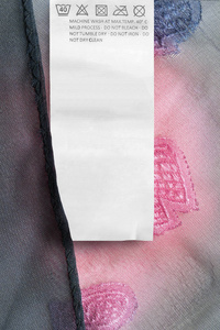 粉色和蓝色纺织品背景特写上的护理服装标签