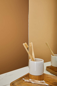 镶有竹制牙刷的木耳板白色大理石桌上的镜子和米色背景