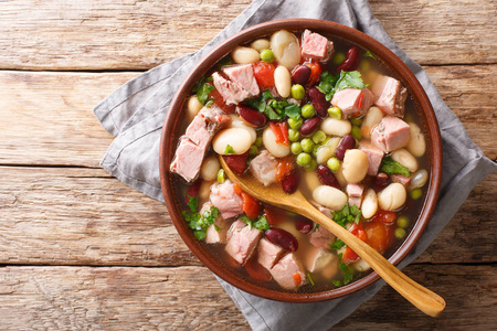 美味的豆汤，配上火腿西红柿和草药，放在桌子上的一个碗里。 水平顶部视图，Abov
