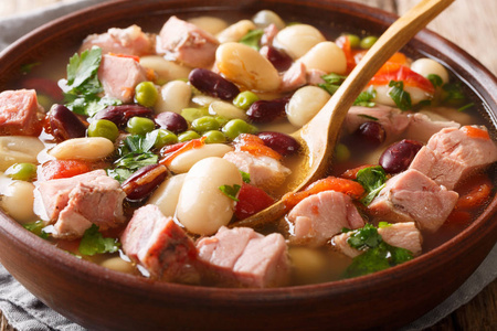 自制的慢豆汤，配上火腿西红柿和草药，放在桌子上的一个碗里。 水平