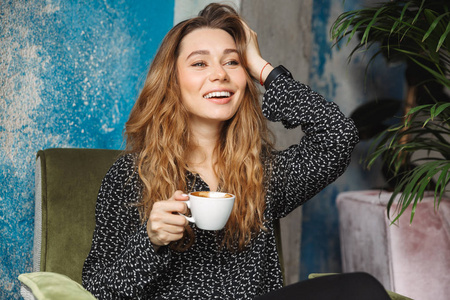 美丽的年轻漂亮女人坐在咖啡馆里喝咖啡的照片。