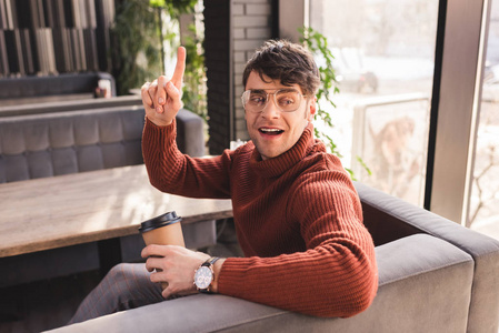 戴眼镜的快乐男人拿着纸杯在咖啡馆打手势