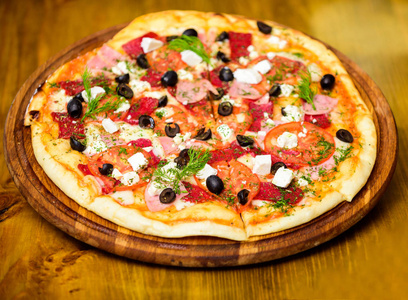 披萨配上了。披萨配西红柿黑橄榄和火腿。带走食物的概念。比萨饼店餐厅。意大利比萨饼的概念。在木板板上的美味热比萨饼。送餐服务