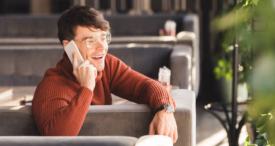 微笑的男人坐在咖啡馆里谈论智能手机