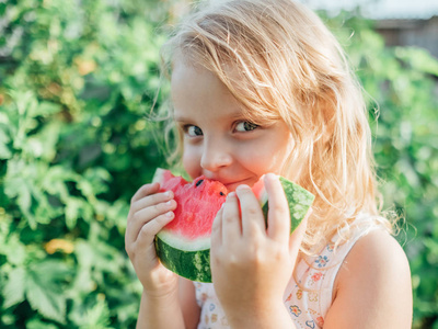 带西瓜的金发小女孩的肖像。 夏日户外儿童，带成熟的红西瓜
