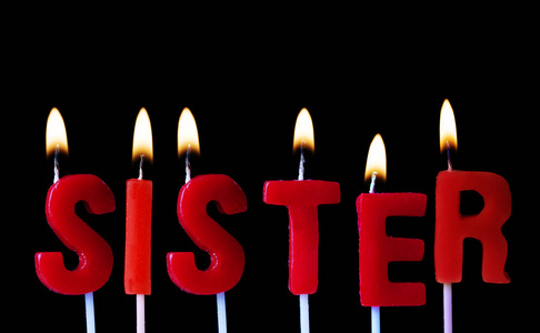 姐姐在红色生日蜡烛在黑色背景下拼出