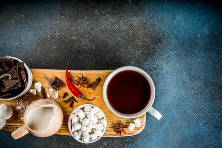 热巧克力杯，碎块巧克力糖，棉花糖红辣椒和香料。 深蓝混凝土背景图