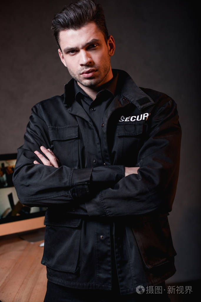 穿着制服的严肃警卫交叉双臂看着摄像机