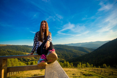 一位留着长发的年轻女子站在木梯边欣赏美丽的山景