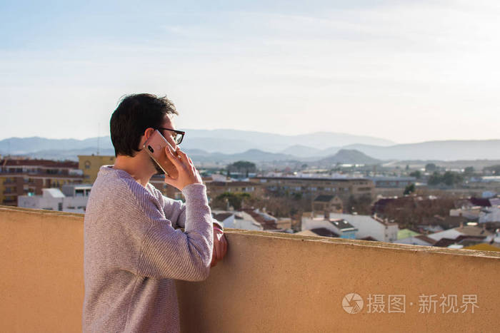 一个站在屋顶上打电话的人的画像.阳台,说话.