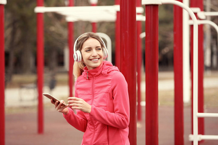 带耳机在运动场听音乐的年轻女子