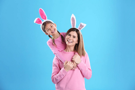 快乐的女人和女儿，有兔子耳朵的颜色背景