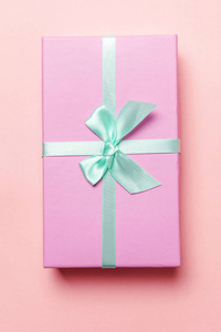 圣诞节新年生日情人节庆祝礼物浪漫的概念。 小礼品盒包装的粉红色纸隔离在粉红色的糊彩彩色潮流背景上。 平躺顶视复印空间